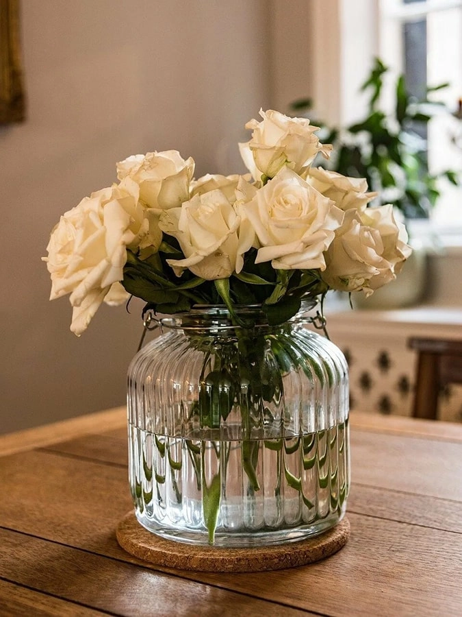 Weiße Rosen in der Vase stehen auf dem Tisch neben dem Fenster in der Küche