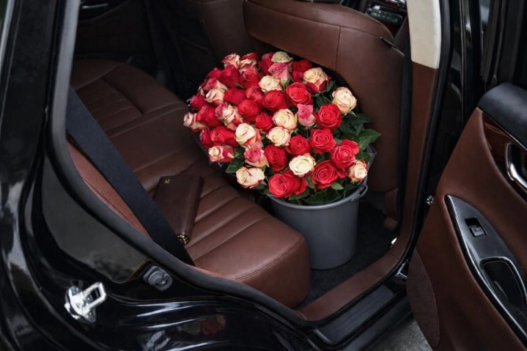 Blumenstrauß im Auto transportieren – Rosenstrauß im Eimer sicher im Fußraum hinter dem Beifahrersitz platziert