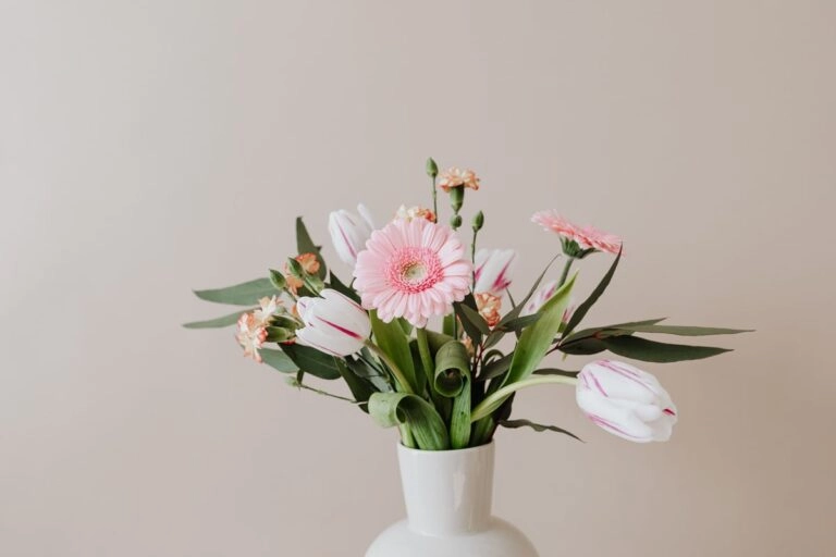 Januarstrauß in weißer Vase: Nelken, rot-weiß gestreifte Tulpen, eine rosa Gerbera und Eukalyptus